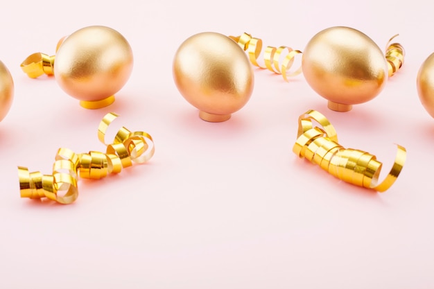 Huevos de oro sobre un fondo rosa, decorado con cintas de oro. El concepto de Pascua y el símbolo de vacaciones.
