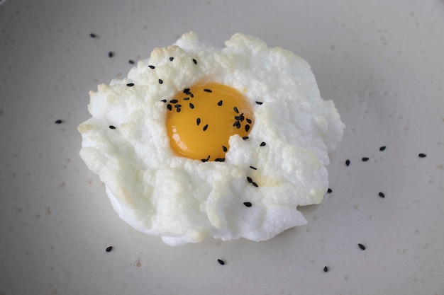 Huevos Orsini en un plato con semillas de sésamo negro Nube de huevo al horno