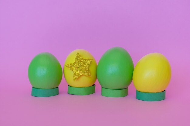 Huevos de Pascua en amarillo y verde en posición vertical decorados con una estrella sobre un fondo rosa