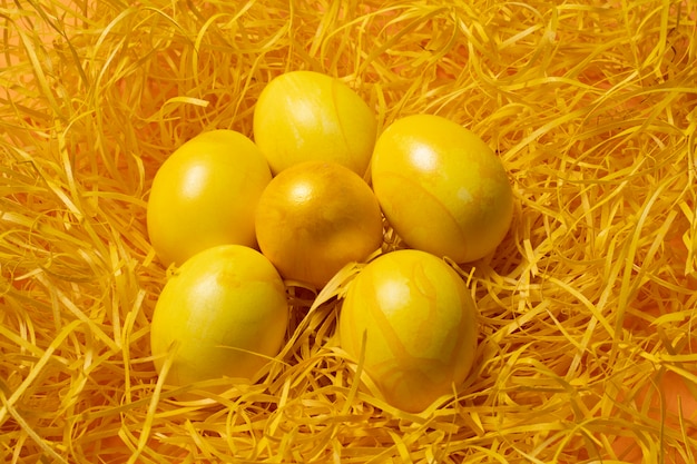 Huevos de Pascua amarillos sobre fondo de paja