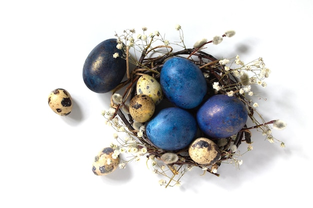 Huevos de Pascua azules decorativos en un nido sobre un fondo blanco.