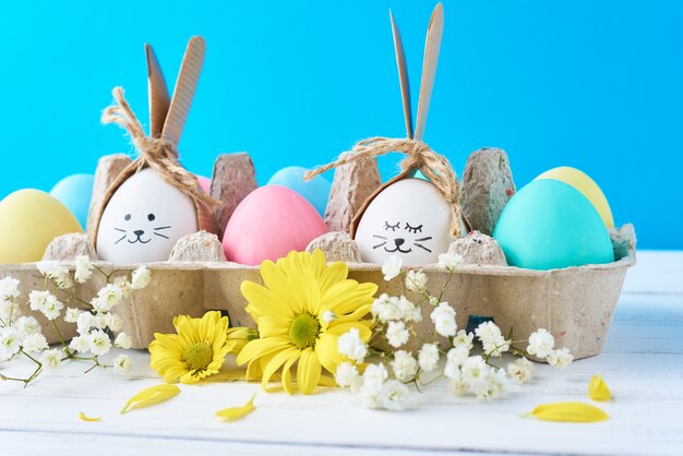 Huevos de Pascua en bandeja de papel con decoración en una pared azul