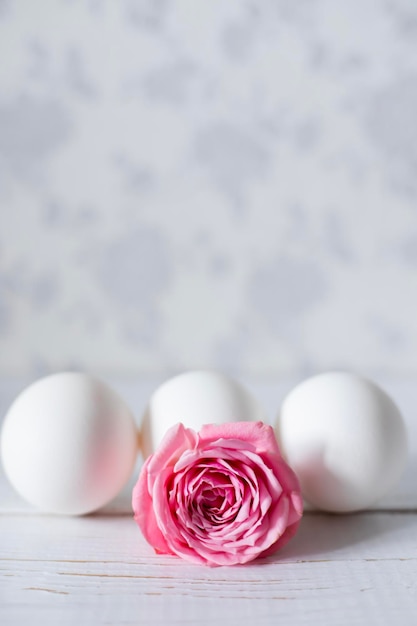 Huevos de Pascua blancos en una bandeja de madera y una rosa