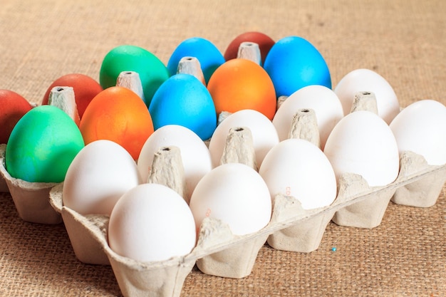 Huevos de Pascua blancos y de colores en cajas de huevos en cilicio