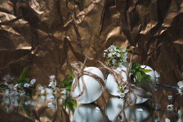 Huevos de Pascua blancos con flores sobre fondo dorado de cerca