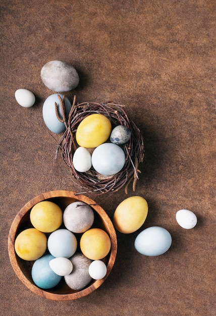 Huevos de pascua brillantes pintados con tintes naturales yacen en un nido