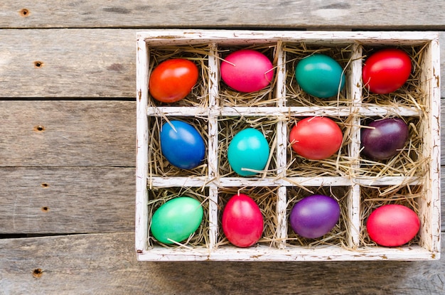 Huevos de pascua en una caja de madera con heno iluminado por la luz del día