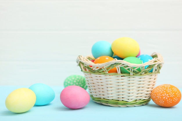 Huevos de Pascua en una canasta y flores sobre la mesa