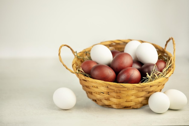 Foto huevos de pascua en una canasta de mimbre sobre fondo blanco con huevos blancos cerca