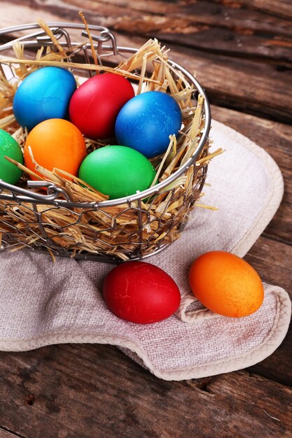 Huevos de Pascua en canasta sobre fondo de tablones de madera vintage