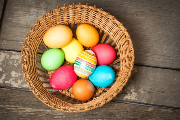 Huevos de Pascua en la canasta sobre tablas de madera