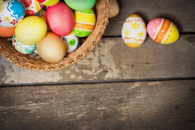 Huevos de Pascua en la canasta sobre tablas de madera