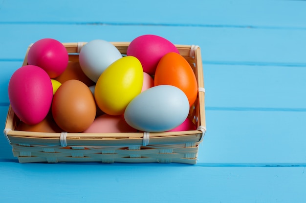 Huevos de Pascua en la cesta en la pared de madera azul