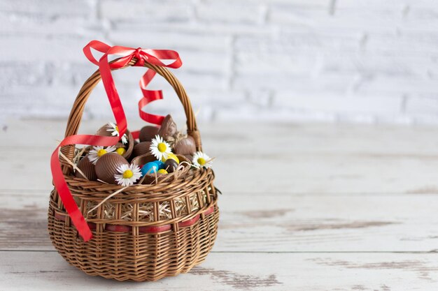 Huevos de Pascua de chocolate en canasta sobre fondo de madera Tarjeta de felicitación de Pascua