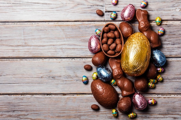 Foto huevos de pascua de chocolate y conejitos sobre un fondo de madera rústica