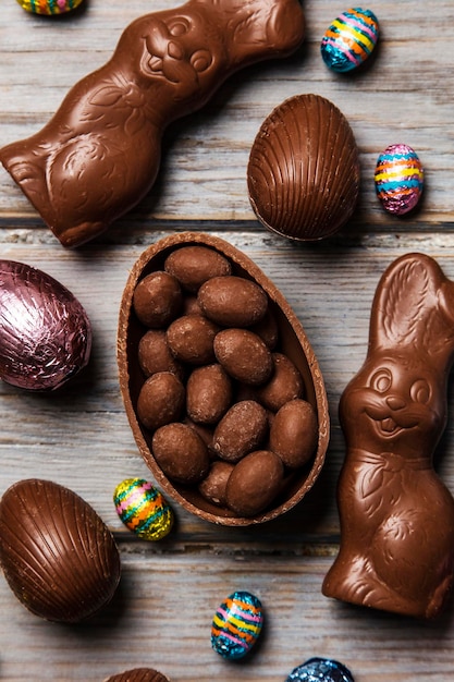 Huevos de pascua de chocolate y conejitos sobre un fondo de madera rústica