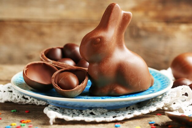 Huevos de Pascua de chocolate y conejo en placa sobre fondo de madera