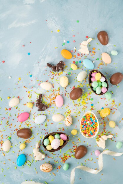 huevos de pascua de chocolate conejos y dulces sobre un fondo de hormigón azul Composición de Pascua Espacio de copia
