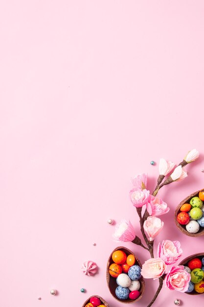 Huevos de pascua de chocolate y decoración plana para niños concepto de huevo de caza de pascua sobre fondo rosa Dulces en forma de huevo