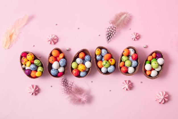 Huevos de pascua de chocolate y decoración plana para niños concepto de huevo de caza de pascua sobre fondo rosa Dulces en forma de huevo