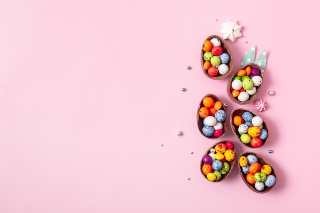Huevos de pascua de chocolate y decoración plana para niños concepto de huevo de caza de pascua sobre fondo rosa Dulces en forma de huevo
