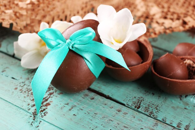 Foto huevos de pascua de chocolate con flores en primer plano de la mesa de madera