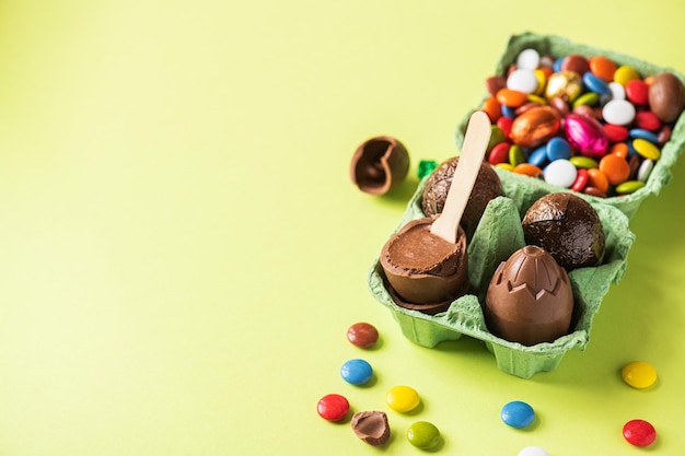 Huevos de Pascua de chocolate con relleno de crema y caramelos de colores sobre un fondo verde Vista superior