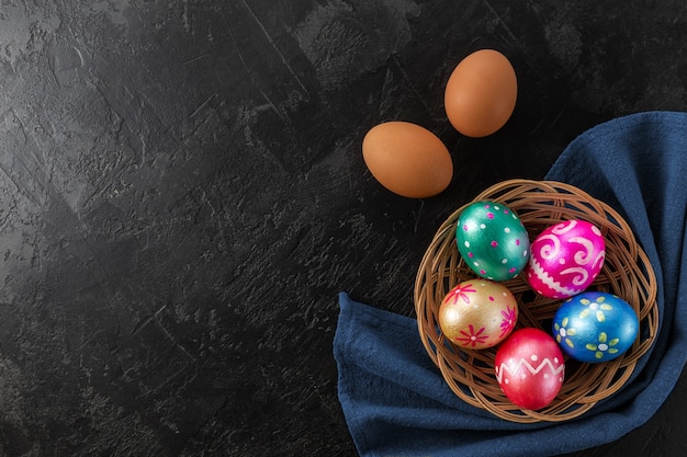 Huevos de Pascua de color azul oscuro, verde, naranja, magenta y dorado de moda decorados en canasta