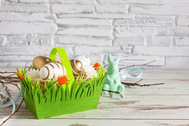 Huevos de Pascua de color dorado y conejito de Pascua en una canasta verde Fondo de Pascua Copyspace