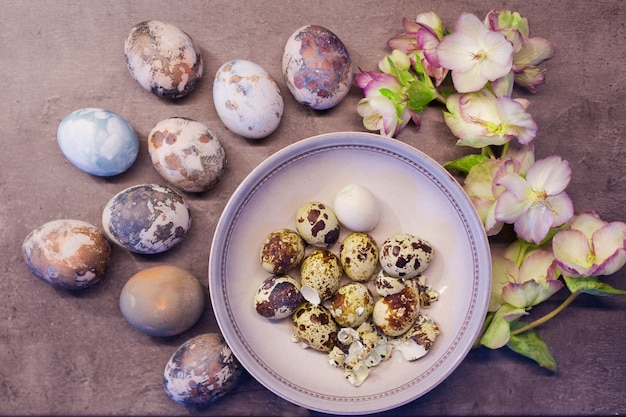 Huevos de Pascua de color natural pintado a mano con piel de cebolla y con flores frescas sobre fondo de hormigón concepto de primavera