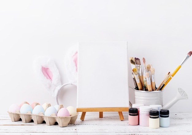 Huevos de Pascua de color pastel y flores de mimosa con marco blanco en blanco para la vista frontal del diseño de la maqueta sobre fondo de pared de ladrillo blanco