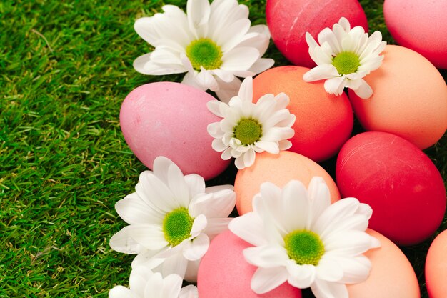 Huevos de Pascua coloreados sobre hierba decorada con flores