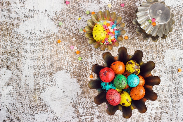 Huevos de pascua de colores y moldes para hornear sobre un fondo de lona ligera