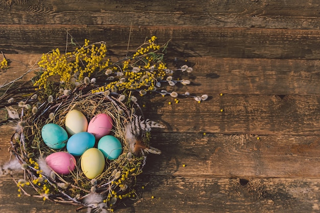 Huevos de Pascua de colores en el nido. En el contexto de una tabla de madera.