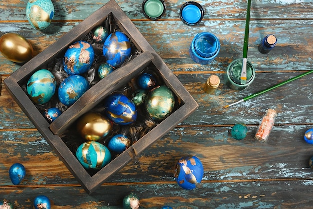 Huevos de Pascua de colores pintados en caja de madera oscura sobre fondo de madera oscura Estilo boho