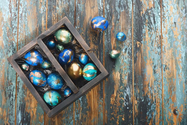 Huevos de Pascua de colores pintados en caja de madera oscura sobre fondo de madera oscura Estilo boho