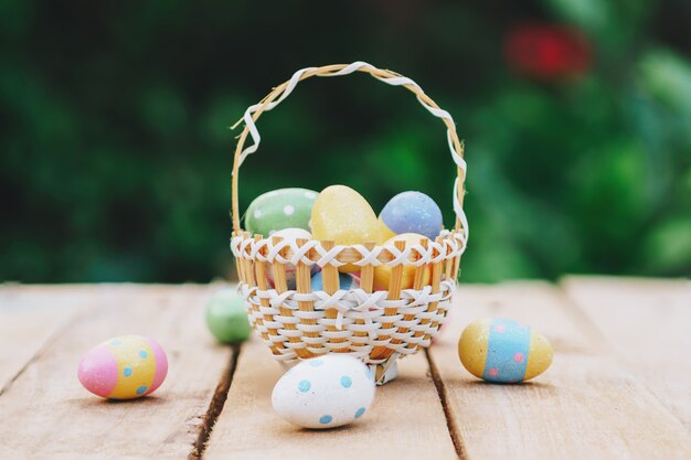 Los huevos de Pascua coloridos en cesta en la tabla de madera ganan el espacio de la copia.