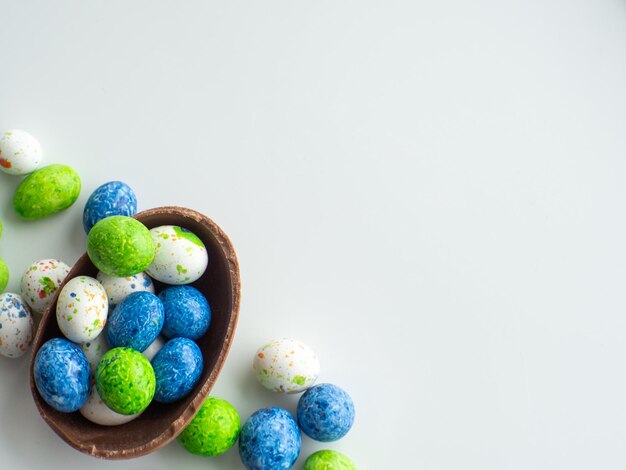 Huevos de pascua coloridos y de chocolate con grageas dulces sobre fondo blanco