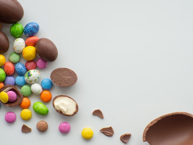 Huevos de pascua coloridos y de chocolate con grageas dulces sobre fondo blanco