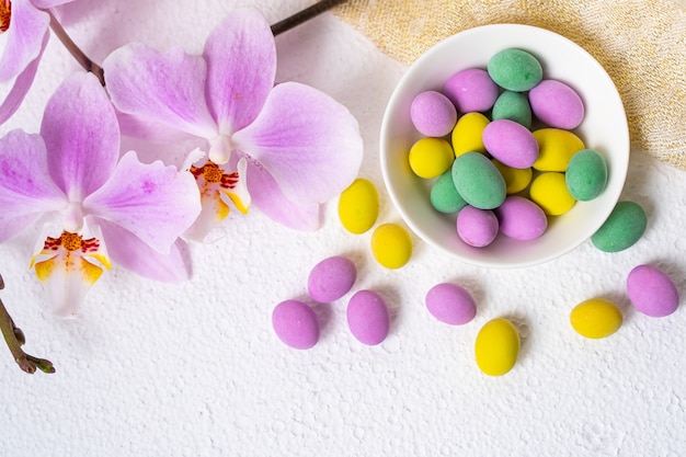 Huevos de Pascua coloridos y flor de la orquídea del phalaenopsis con la placa en el escritorio blanco.