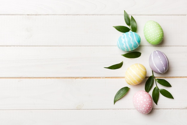 Huevos de Pascua coloridos con hojas de flores de primavera aisladas sobre fondo blanco Borde de vacaciones de huevo de color