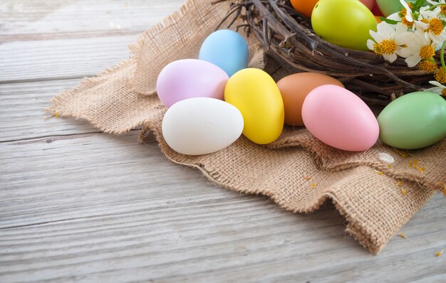 Huevos de Pascua coloridos en jerarquía con la flor en fondo de madera rústico de los tablones.