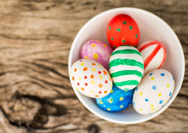 Huevos de pascua coloridos y en mesa de madera