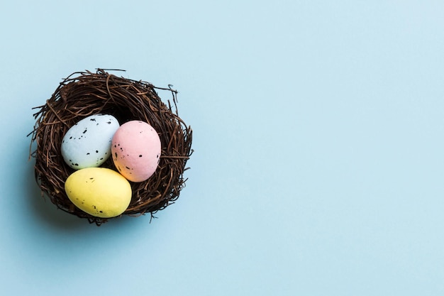 Huevos de Pascua coloridos en el nido en el fondo de la mesa con vista superior del espacio de copia