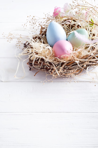 Huevos de Pascua coloridos en pequeña jerarquía con en el fondo de madera blanco, espacio de la copia. Evento festivo