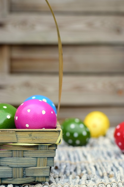 Huevos de Pascua coloridos pintados a mano en una cesta en un fondo de madera.
