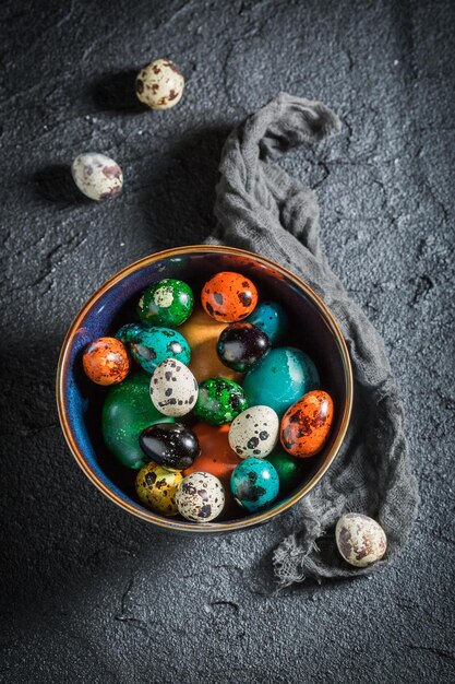 Huevos de Pascua coloridos en tazón azul sobre roca negra