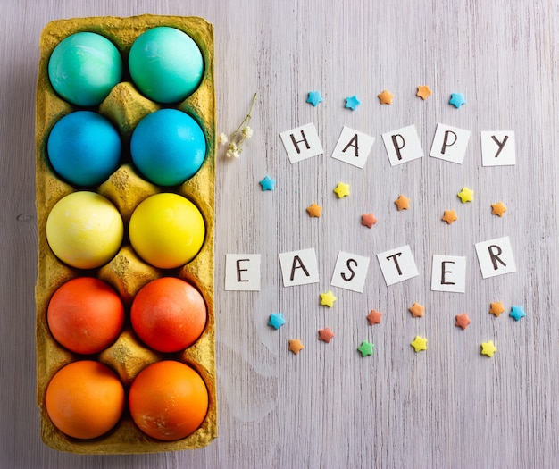 Foto huevos de pascua coloridos, con texto feliz pascua en la madera blanca