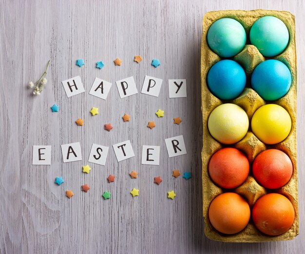 Foto huevos de pascua coloridos, con texto feliz pascua en la madera blanca