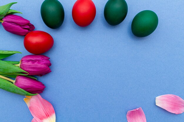 Huevos de Pascua con coloridos tulipanes rosados con espacio de copia en una primavera azul.